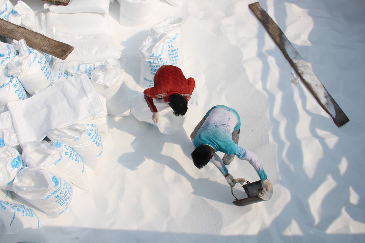 Workers filling and closing white sacks of salt at a salt packing yard