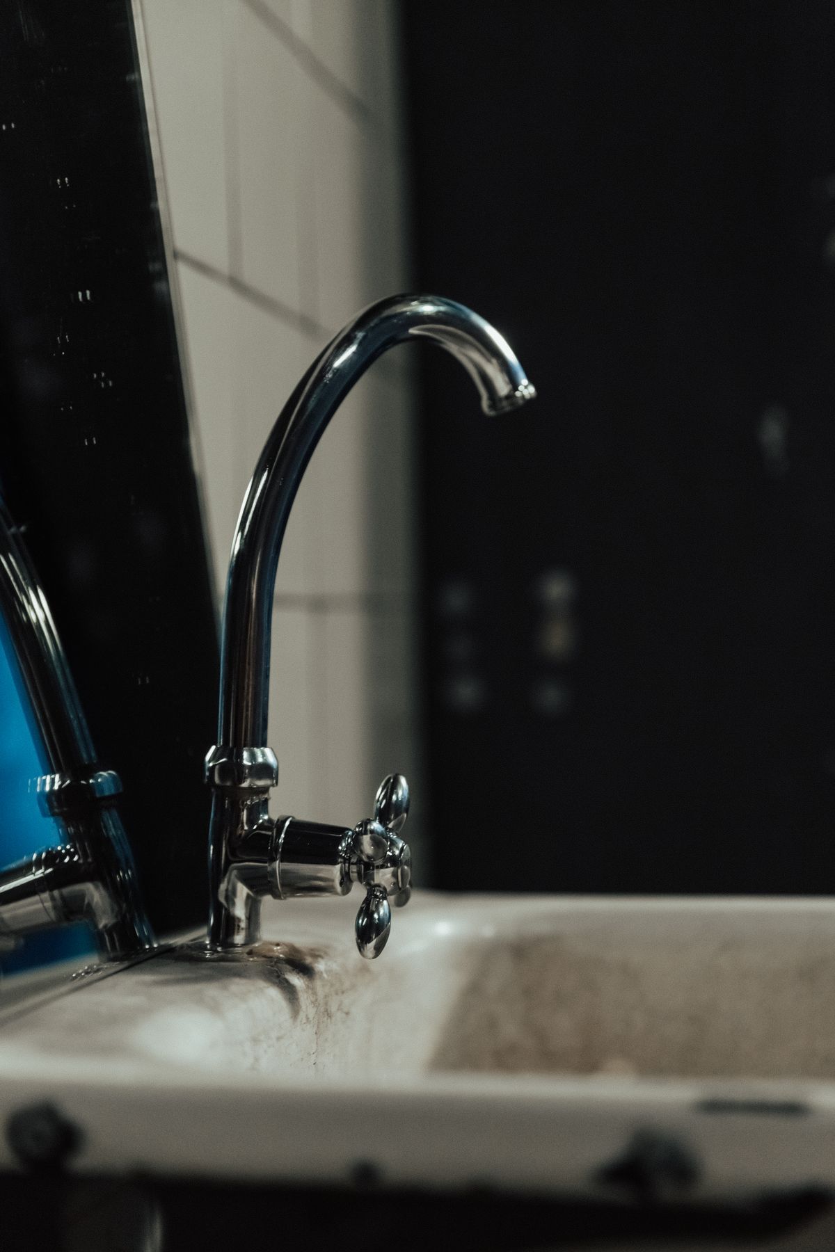 Old chrome faucet above a stained sink with mineral marks, the kind of existing hard-water buildup a salt-free conditioner is not sold to remove