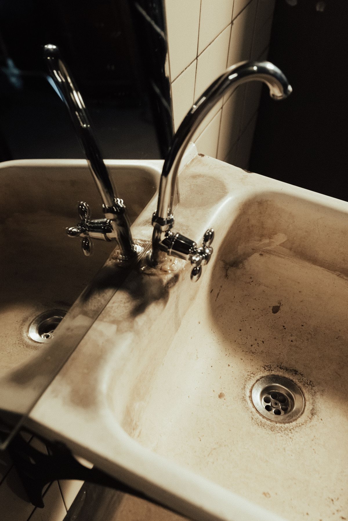 Bathroom washbasin with dark brown-black deposits around the drain and across the bowl, a stain that a manganese test can confirm or rule out