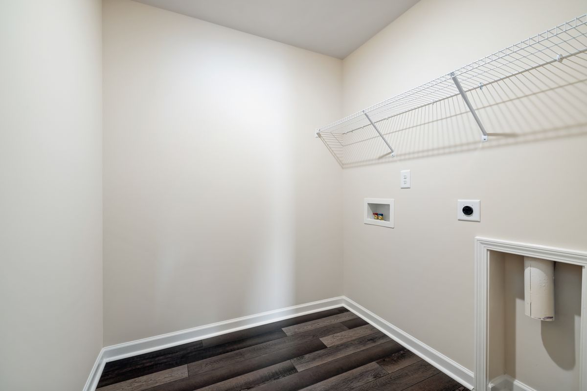 Empty utility room with a washer hookup box and a wall outlet; a two-tank Tier1 water softener needs a drain and 120 V power within reach