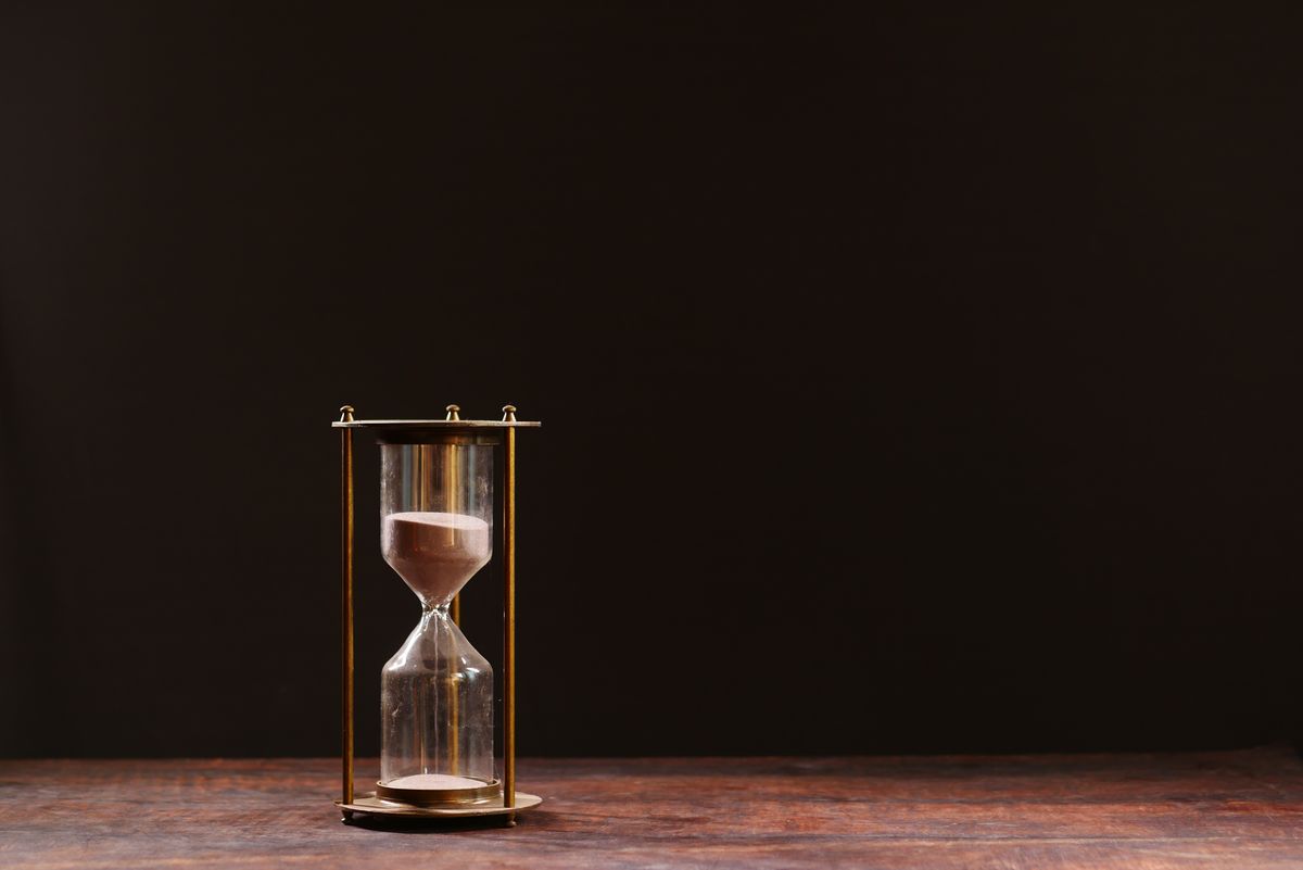 Classic hourglass with sand trickling through against a dark background, representing the working life of water softener resin