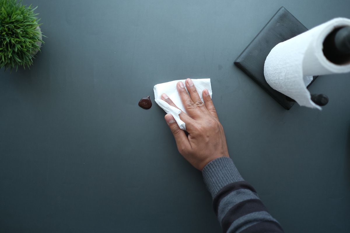 Hand wiping a dark surface dry with a sheet of tissue paper, the same dry-first step that makes the true origin of a control head leak visible