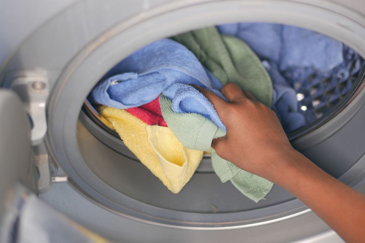 Hands loading towels into a front-loading washing machine
