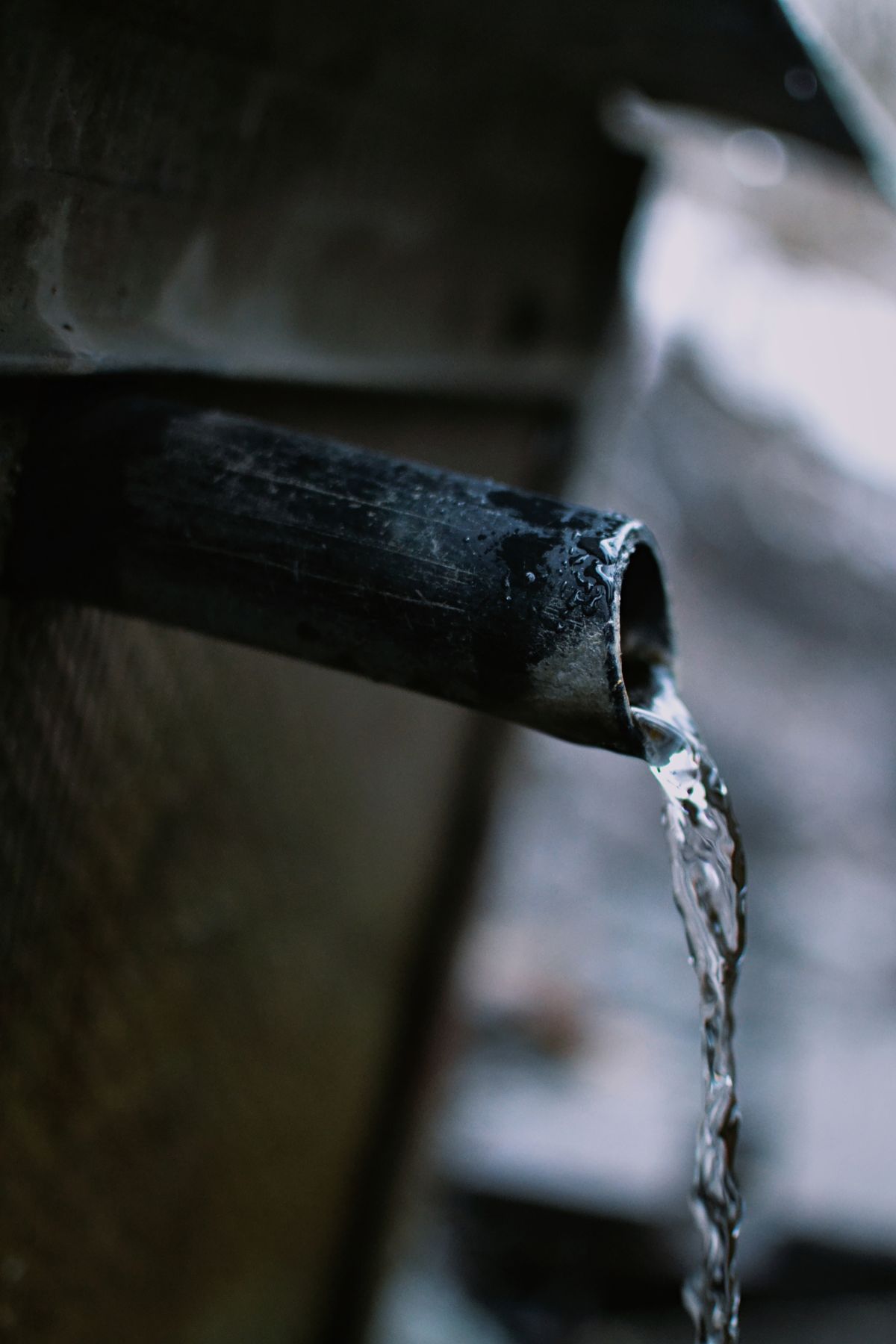 Water streaming from an industrial pipe in a concentrated flow, illustrating the preferred path that resin channeling creates through a softener bed