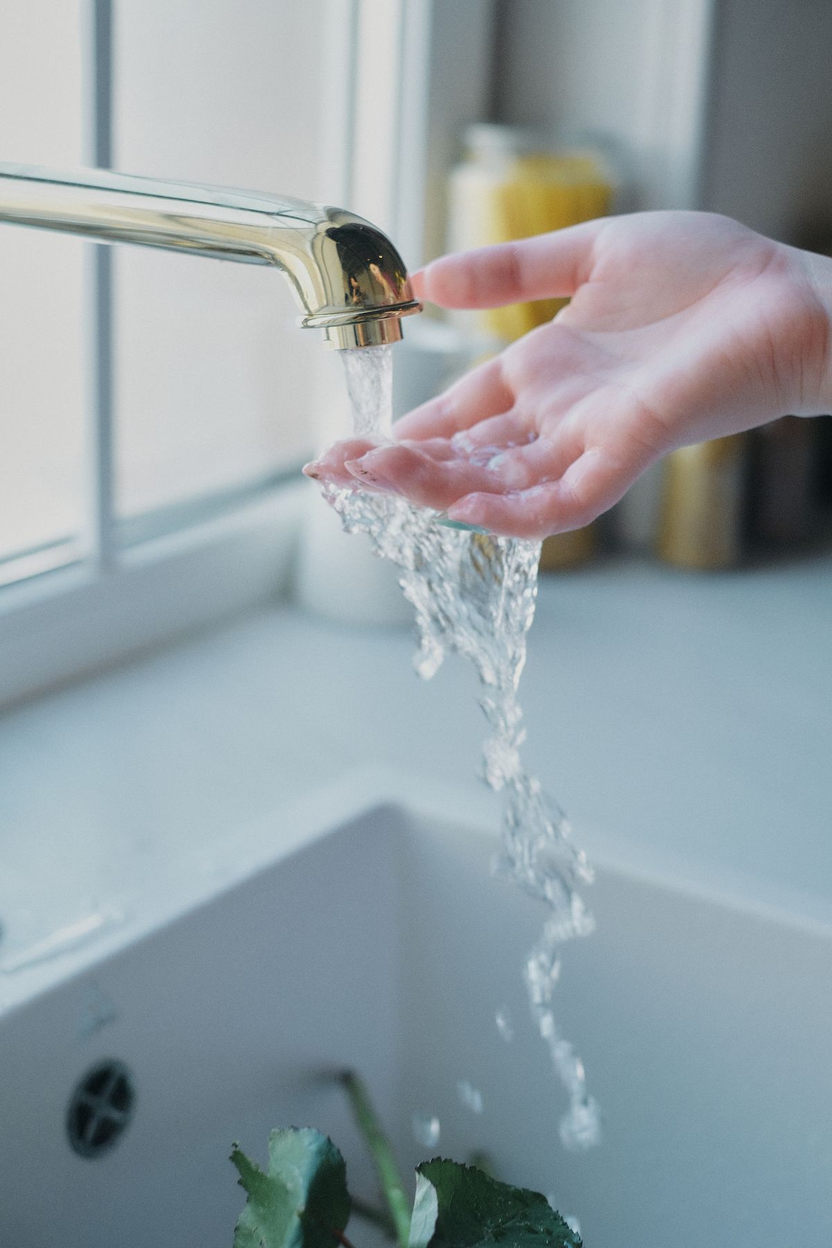 Water flowing over a hand under a kitchen tap, the point where a chlorine taste after a water softener is first noticed