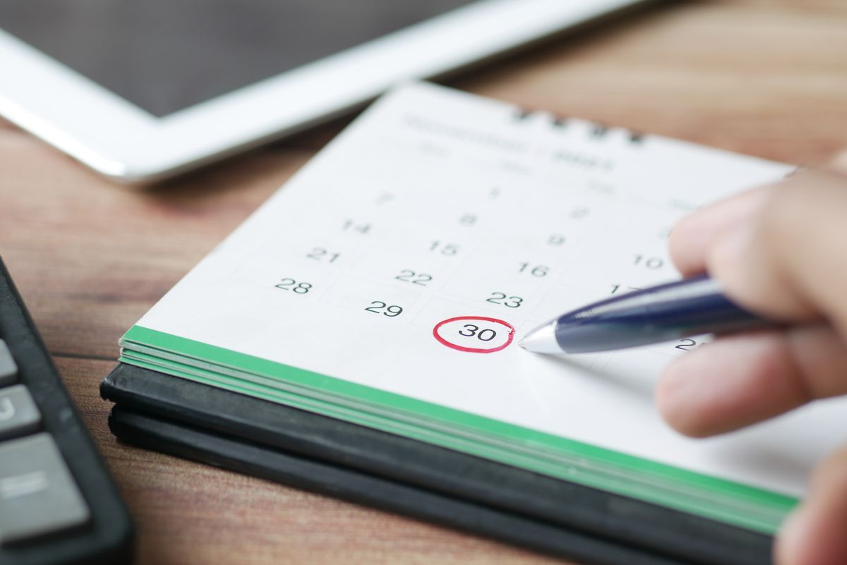 Hand marking a date on a calendar with a pen, the record-keeping step that turns an intermittent hard water complaint into a readable pattern