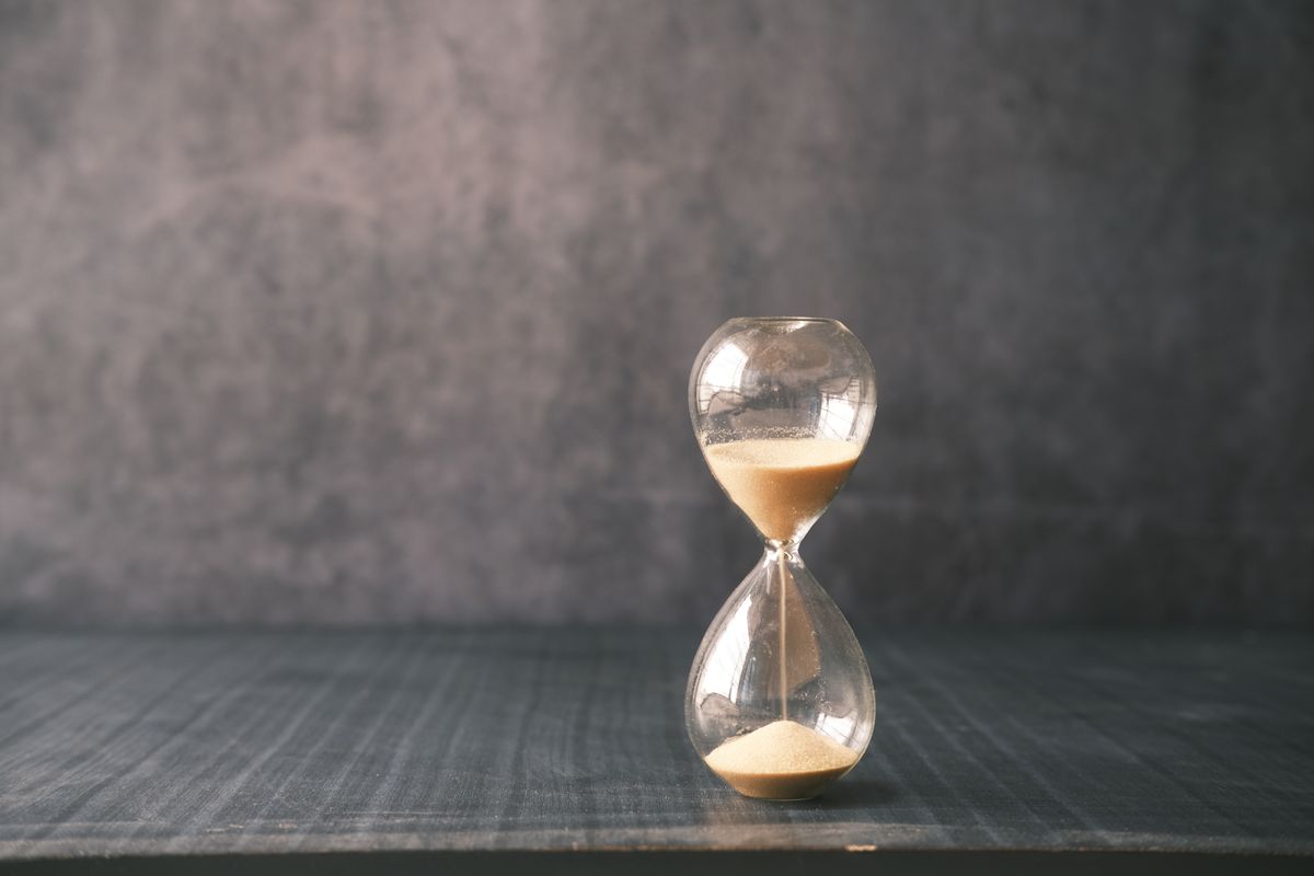 Close-up of a glass hourglass with sand running through it, representing the timing of when a water softener refills its brine tank