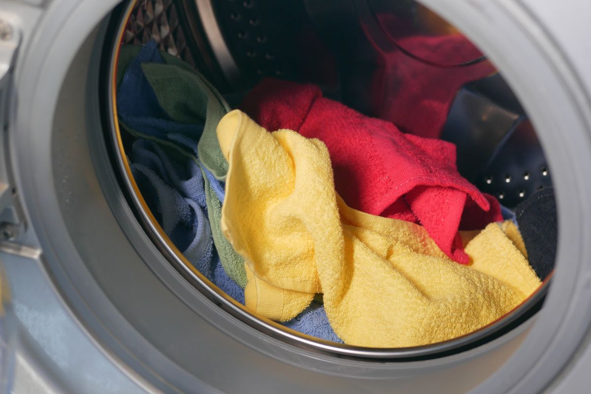 Colourful towels loaded inside a front-loading washing machine drum