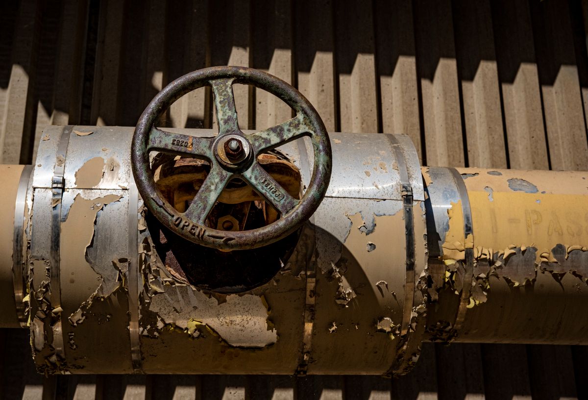 Close-up of a rusted industrial valve on a weathered pipe with peeling paint, the kind of steady iron exposure that sets how often a softener bed needs cleaning