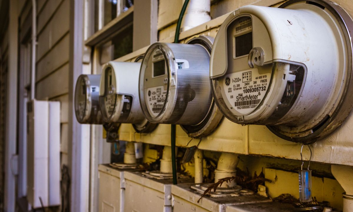 Row of residential electricity meters on a house wall, the meters that record the few kilowatt-hours a water softener control valve uses each year