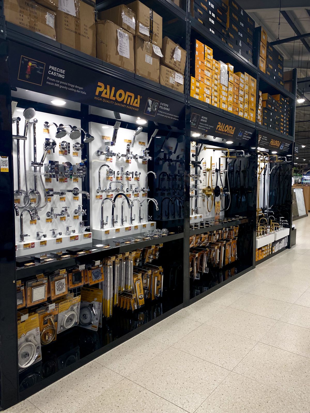 Lit wall display of faucets, shower fittings and plumbing parts in a home-improvement store aisle, the big-box channel where Whirlpool cabinet softeners are sold