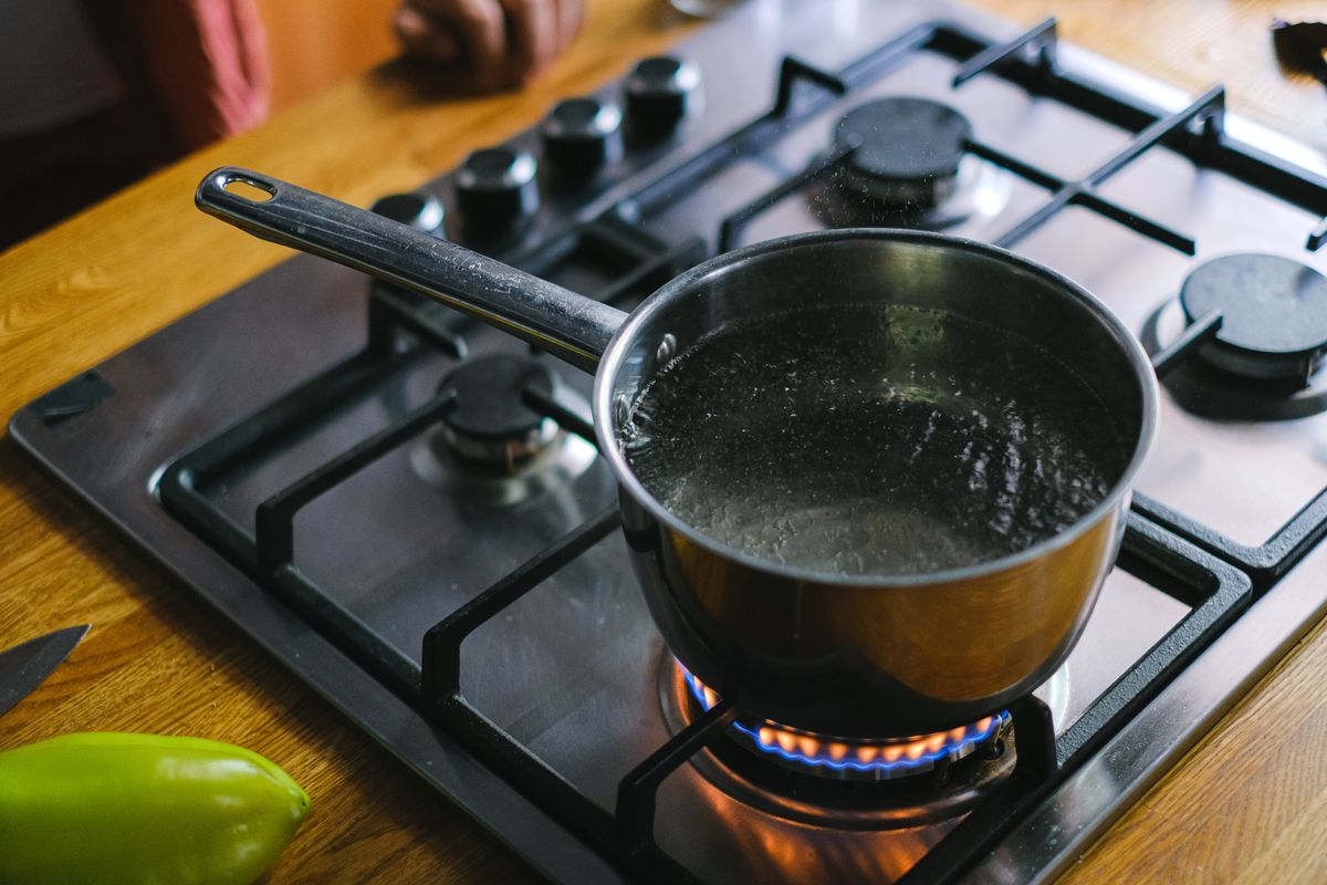 Stainless steel saucepan of water boiling on a gas hob, the kitchen test for whether boiling removes water hardness