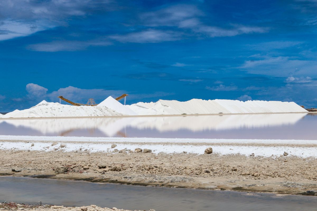 Aerial view of hardened white salt mounds with standing water beside them, the crusted mass that forms when salt fuses into a bridge in a brine tank