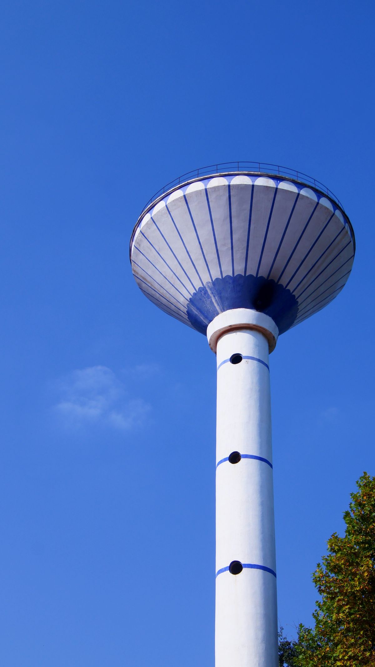 A tall modern water tower against a clear blue sky, the storage that holds treated city water in the mains before it reaches a household softener