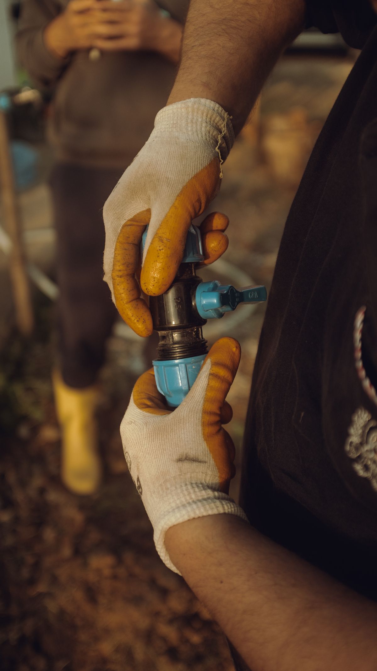 Hands of a worker assembling a water supply pipe outdoors, the kind of main-line plumbing work that often precedes a no-water call after a softener is installed