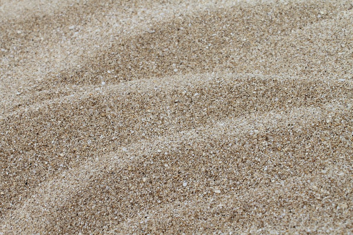 Fine grains of sand in close-up, the kind of suspended sediment a prefilter keeps out of a softener resin bed and control valve