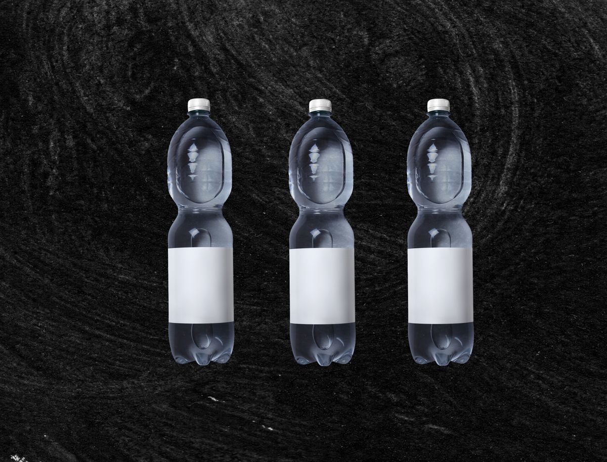 Three plastic bottles of still water with blank white labels standing against a dark textured background
