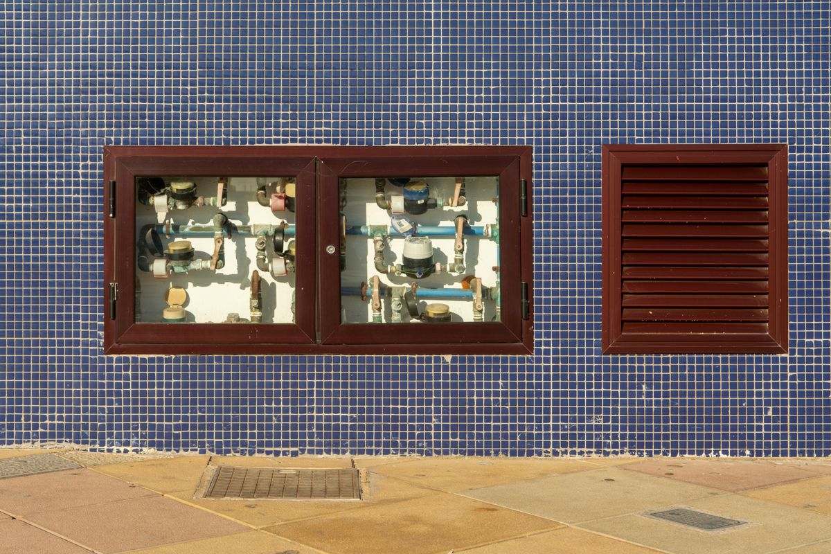 Row of exposed water meters set into a tiled wall, the kind of meter reading that tracks gallons treated between softener regenerations