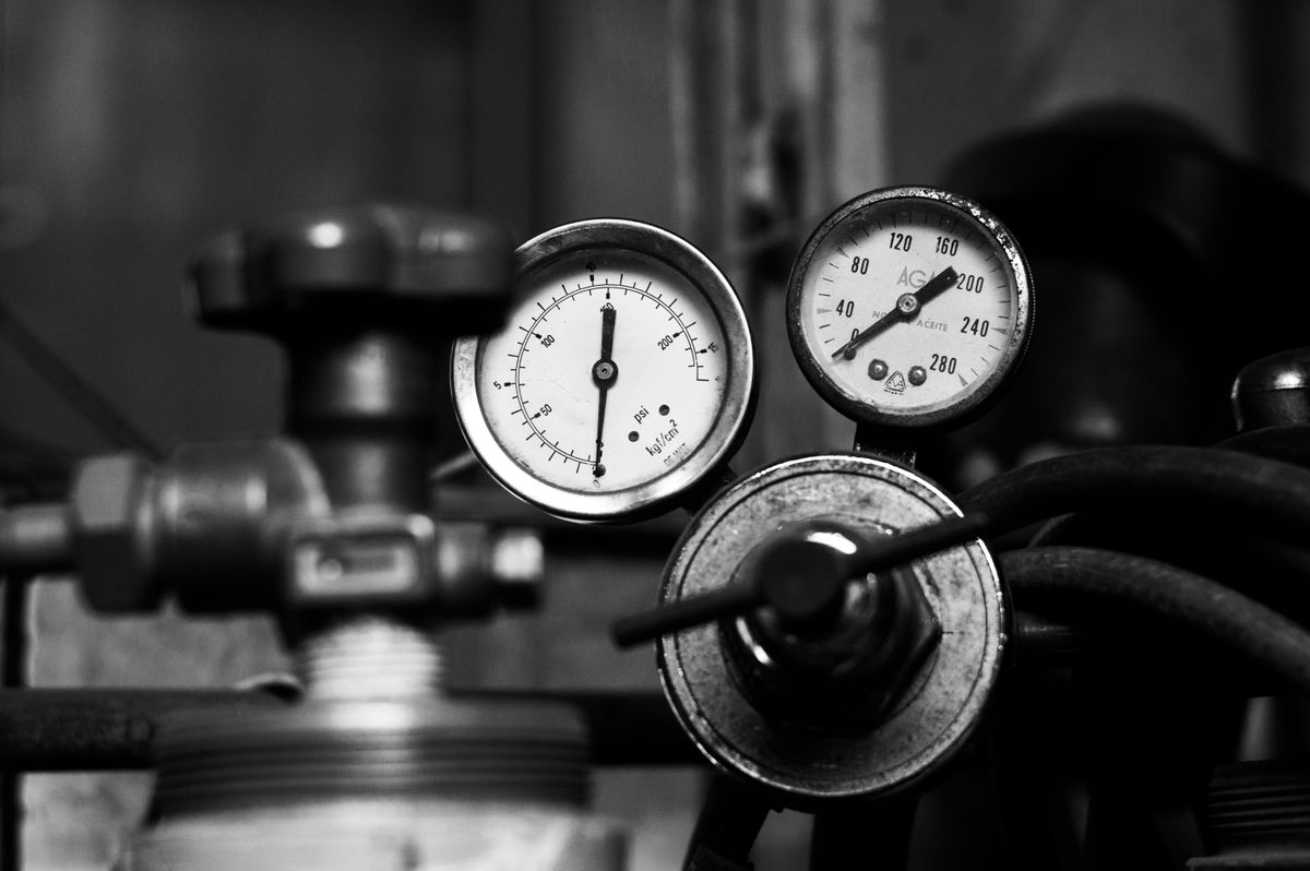 Pair of analog pressure gauges mounted on pipework, the kind of reading that shows whether supply pressure is high enough to make a softener and its pipes hum