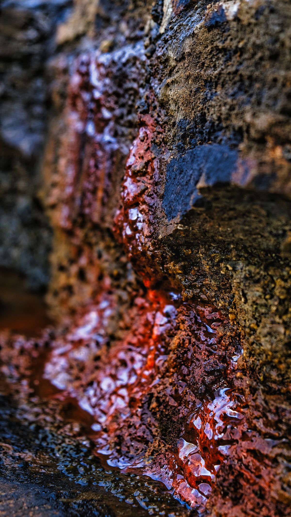 Water seeping over rock stained deep red-orange with iron oxide, the rusted iron that clogs fine mesh water softener resin