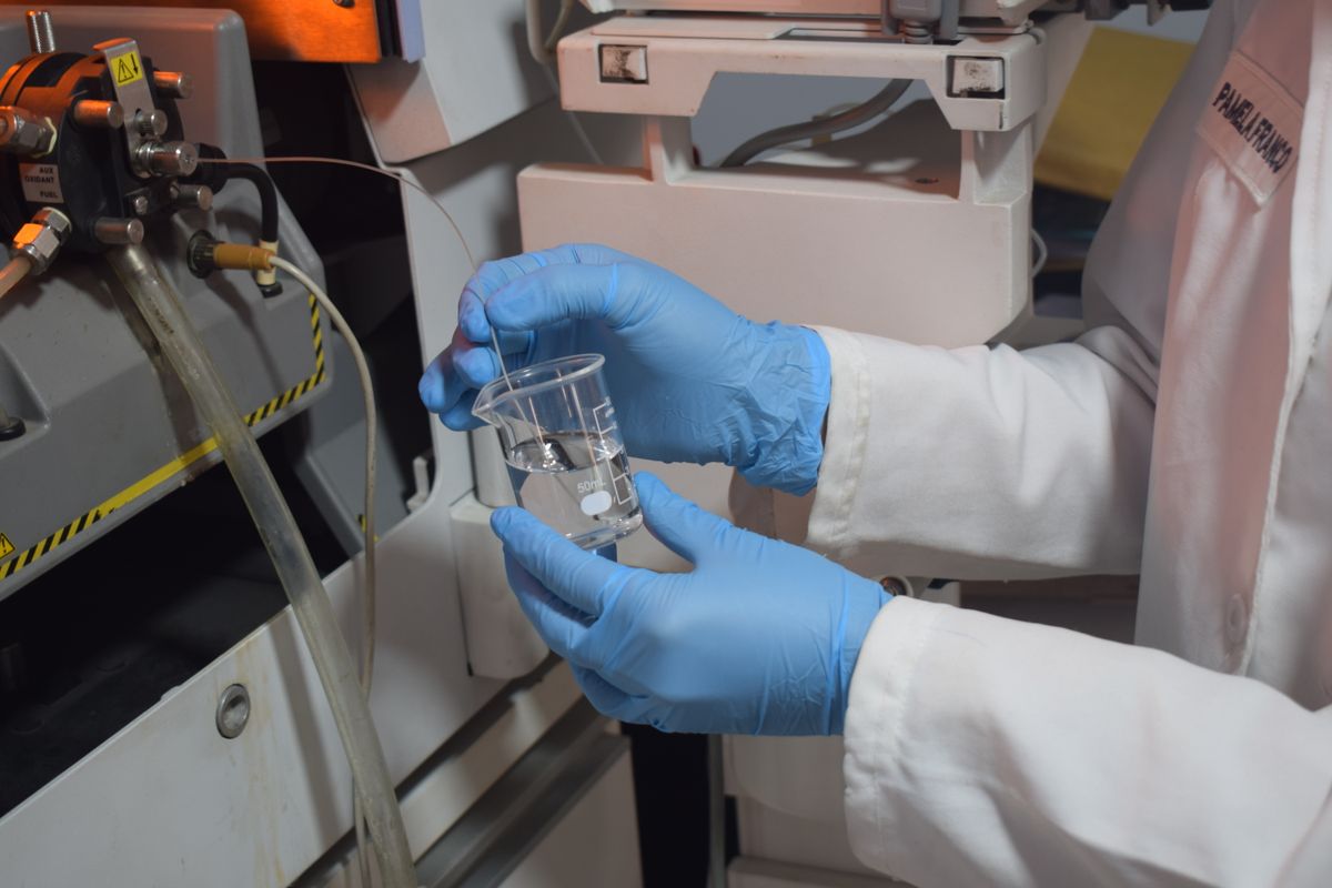 Lab technician pouring a water sample into a vial, the step that separates a home water test from a certified lab test