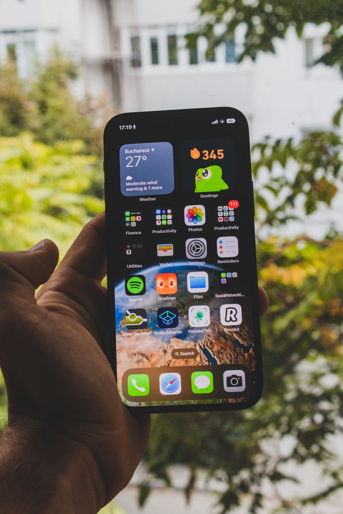 Hand holding a smartphone showing its home screen of app icons; Culligan Connect and EcoWater HydroLink Plus send softener alerts to a phone like this