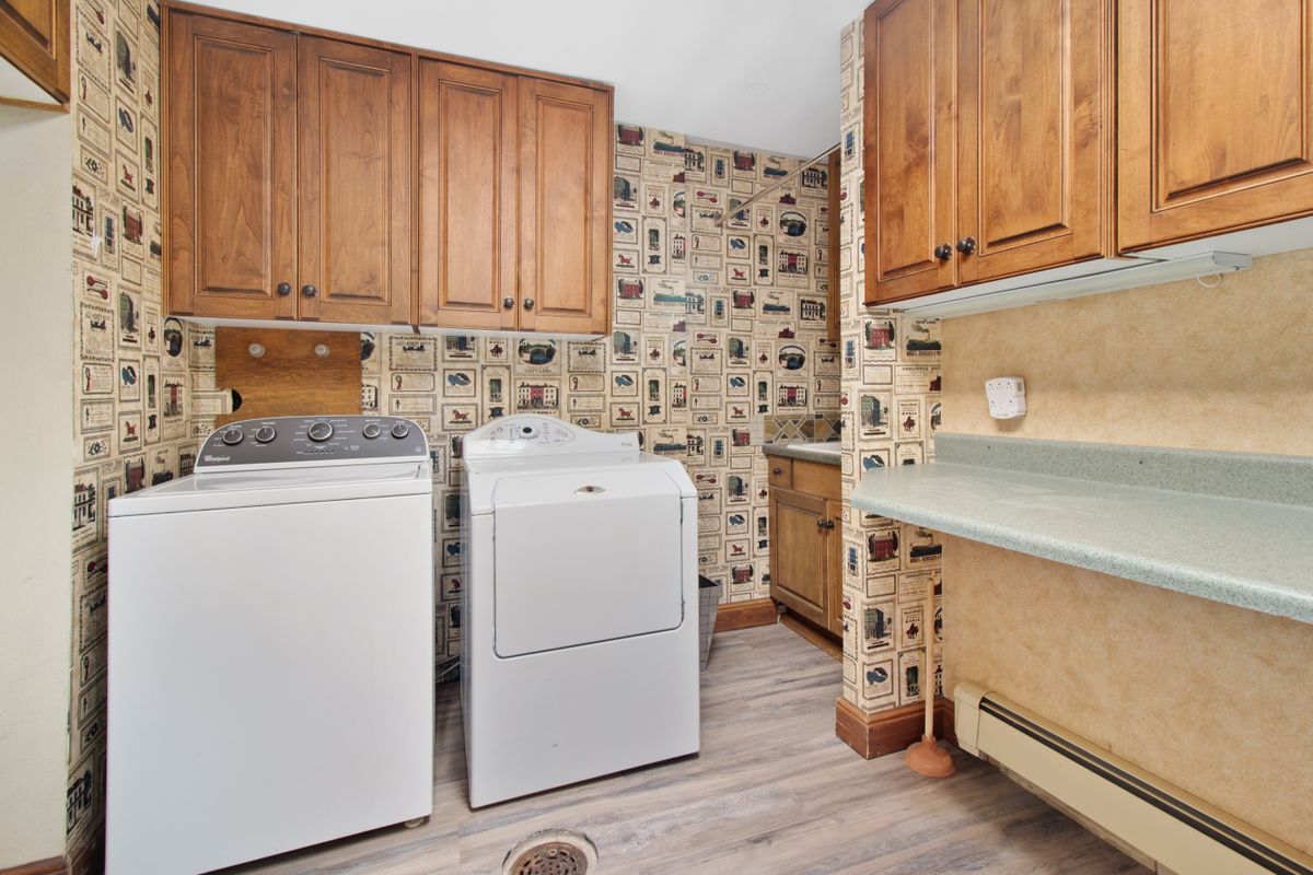 Home laundry room with a washer, dryer, wall cabinets and a floor drain, a heated indoor space with the drain access a water softener location needs