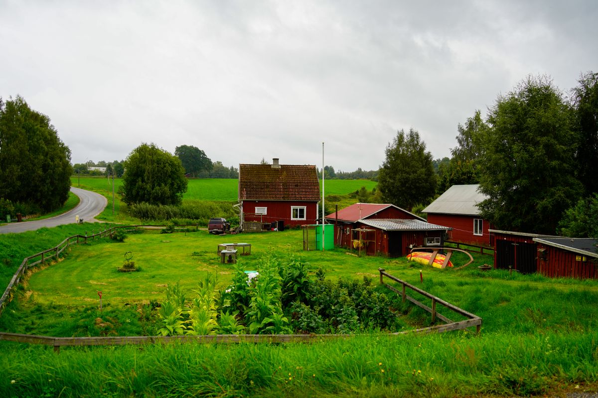 Red farmhouse and outbuildings in green countryside, a rural home on a private well that needs its own water treatment system