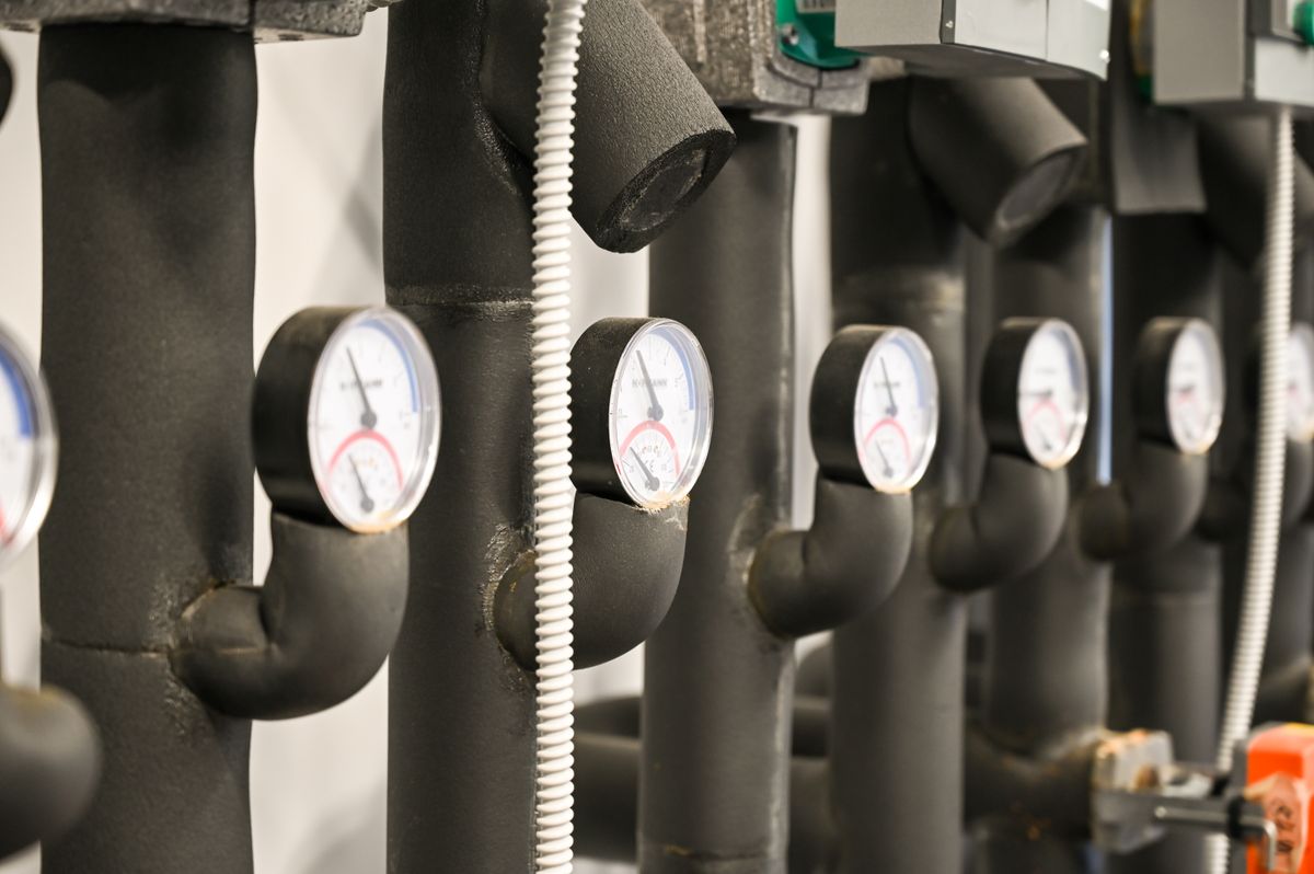 Pressure gauges on insulated supply pipes in a plant room where a chlorine pump, contact tank and carbon tank join the household supply line