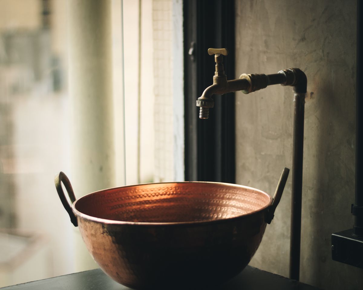 Rustic copper basin with a vintage brass faucet, the plumbing metals that give softened water a metallic taste