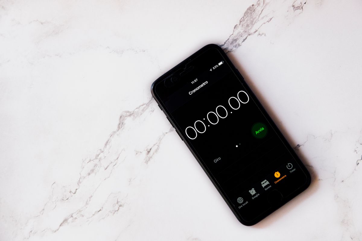 Hand holding a smartphone showing a stopwatch app, the simple timer used to check how long a softener runs its brine refill step