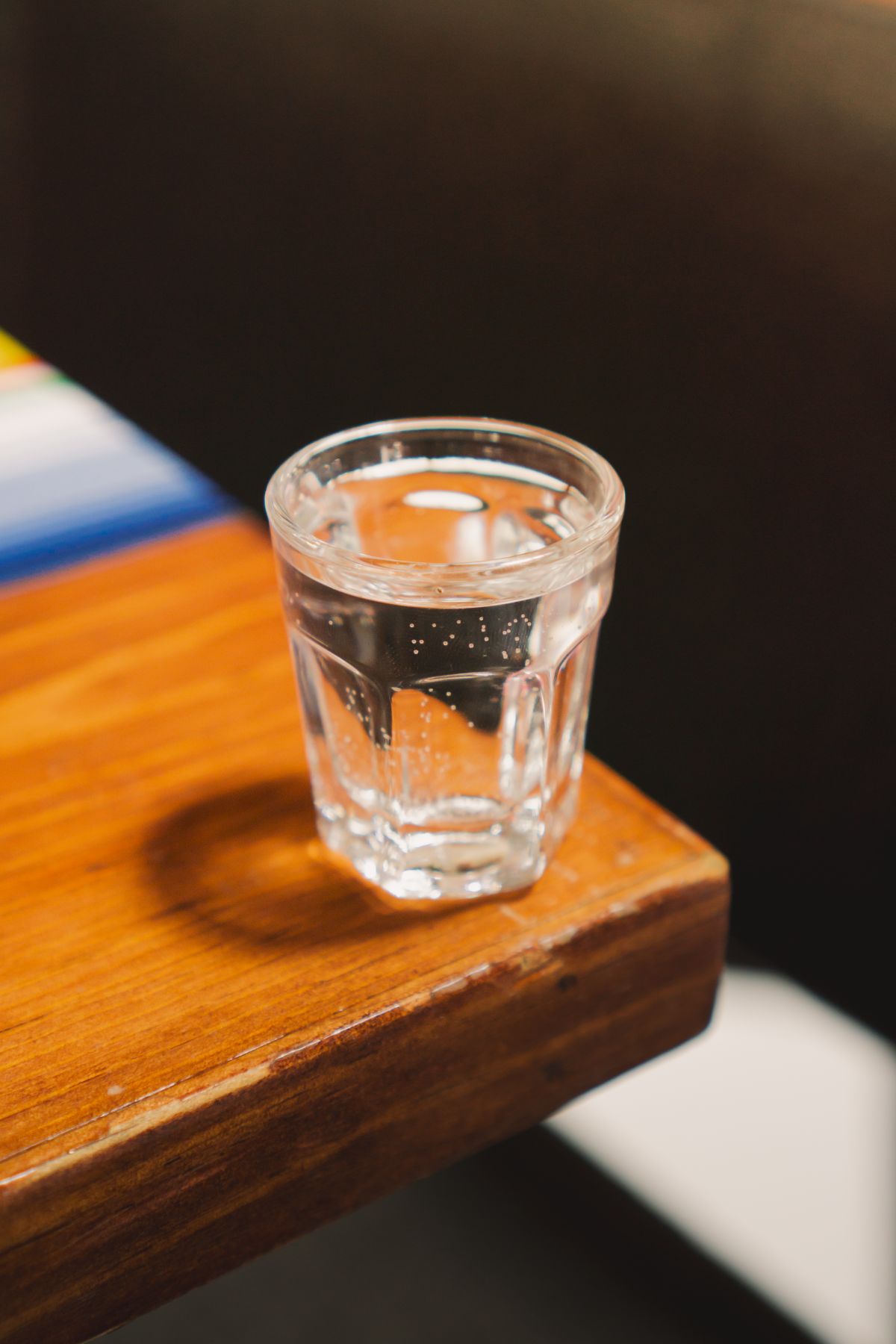 Close-up of a clear glass of water standing on a wooden table, the sample used for the overnight settle test