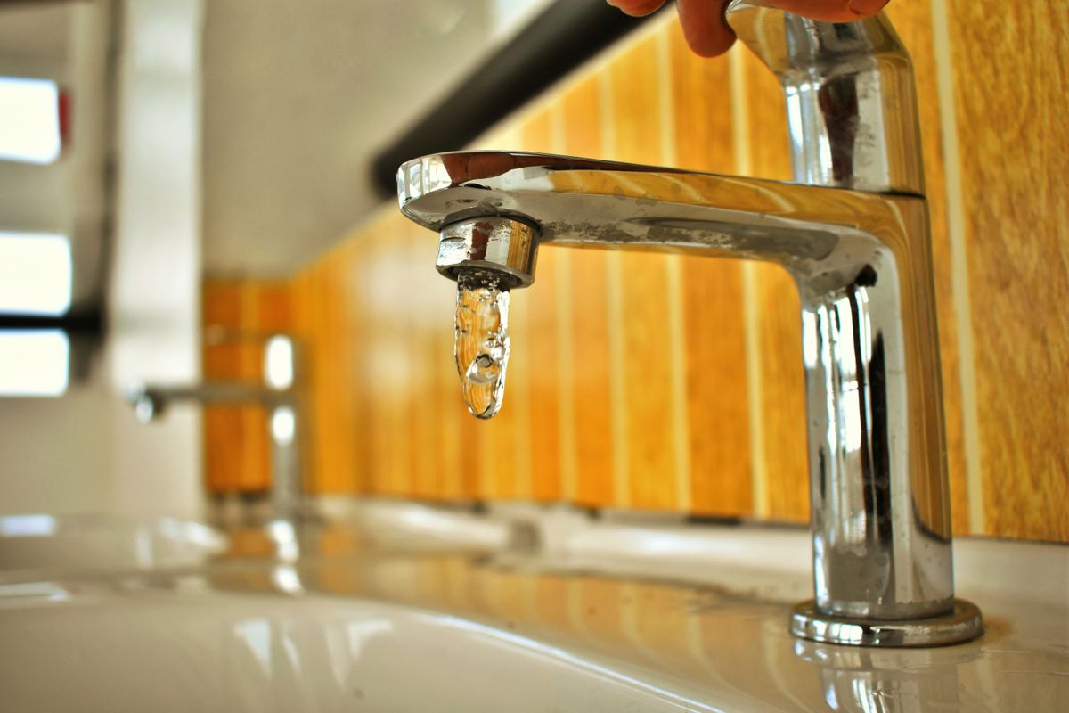 Chrome tap with a water droplet forming at the spout, where resin beads first collect in the aerator screen