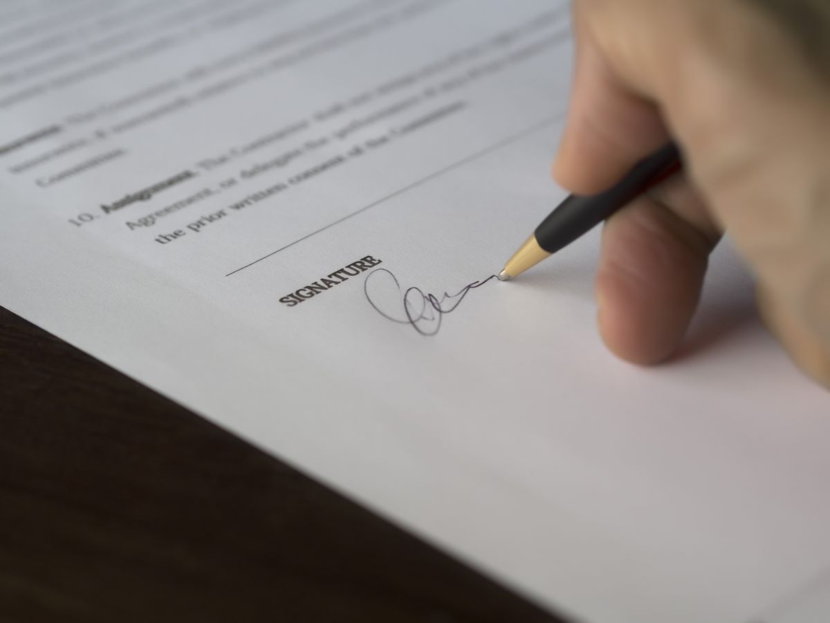 Signing a contract with a pen on a printed agreement, the step to delay until a water softener quote has been compared