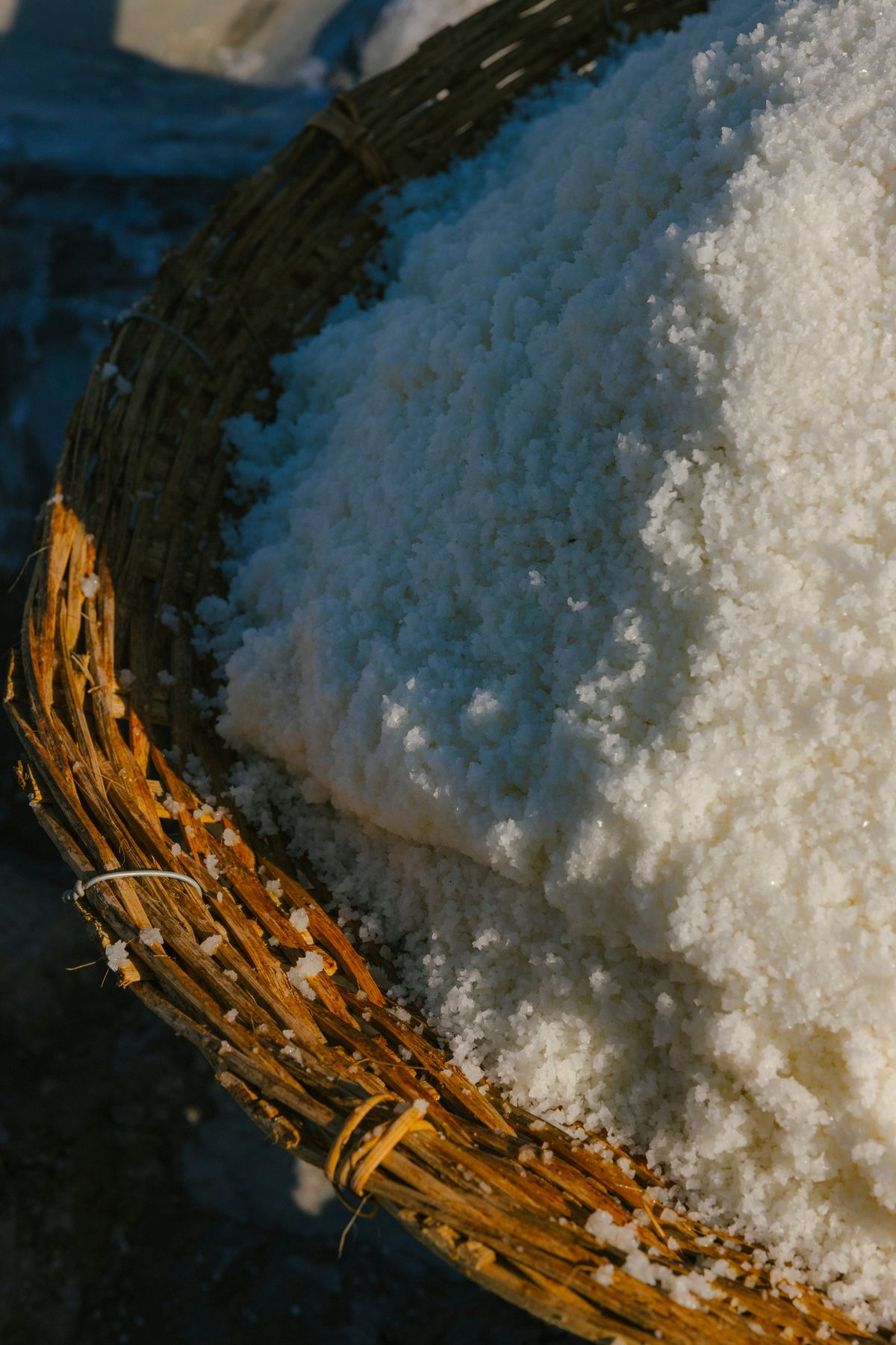 Close-up of coarse white sea salt piled in a wicker basket, a visual reminder of how much softener salt a household should get through in a month
