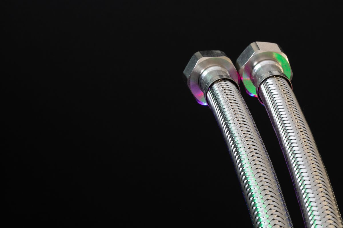 Two braided stainless steel flexible water connectors with hex nut ends, a common way to connect a water softener bypass to rigid supply pipe