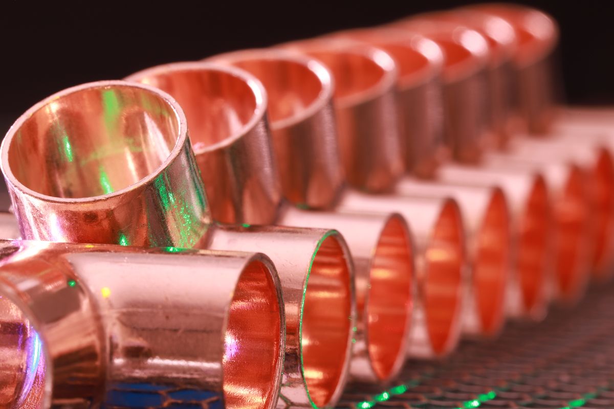 Row of copper pipe couplings and fittings, the kind of joints where a household water line can branch off before the softener