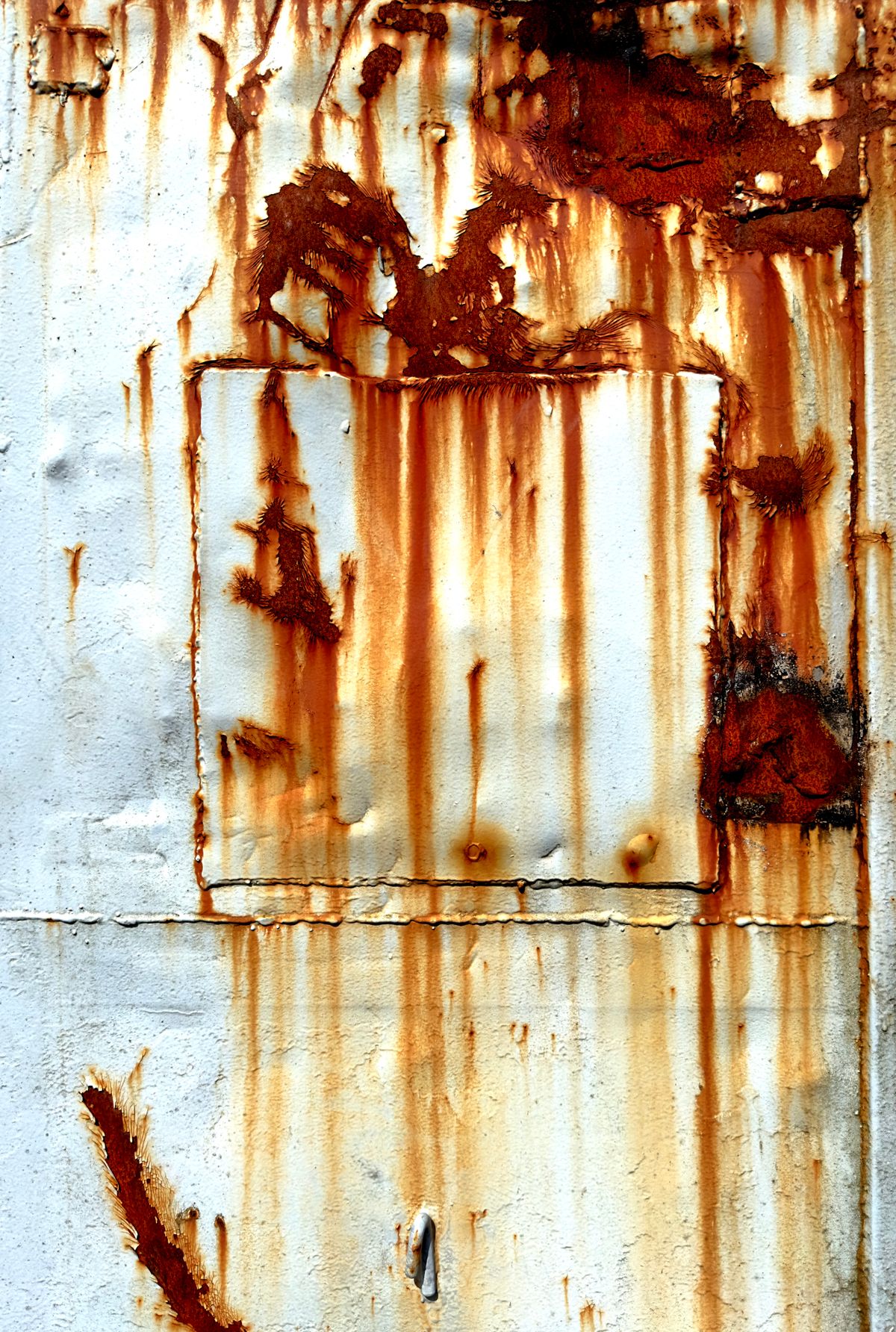 Weathered metal surface streaked with orange rust and mineral staining, the distinctive colour that separates an iron problem from ordinary salt residue