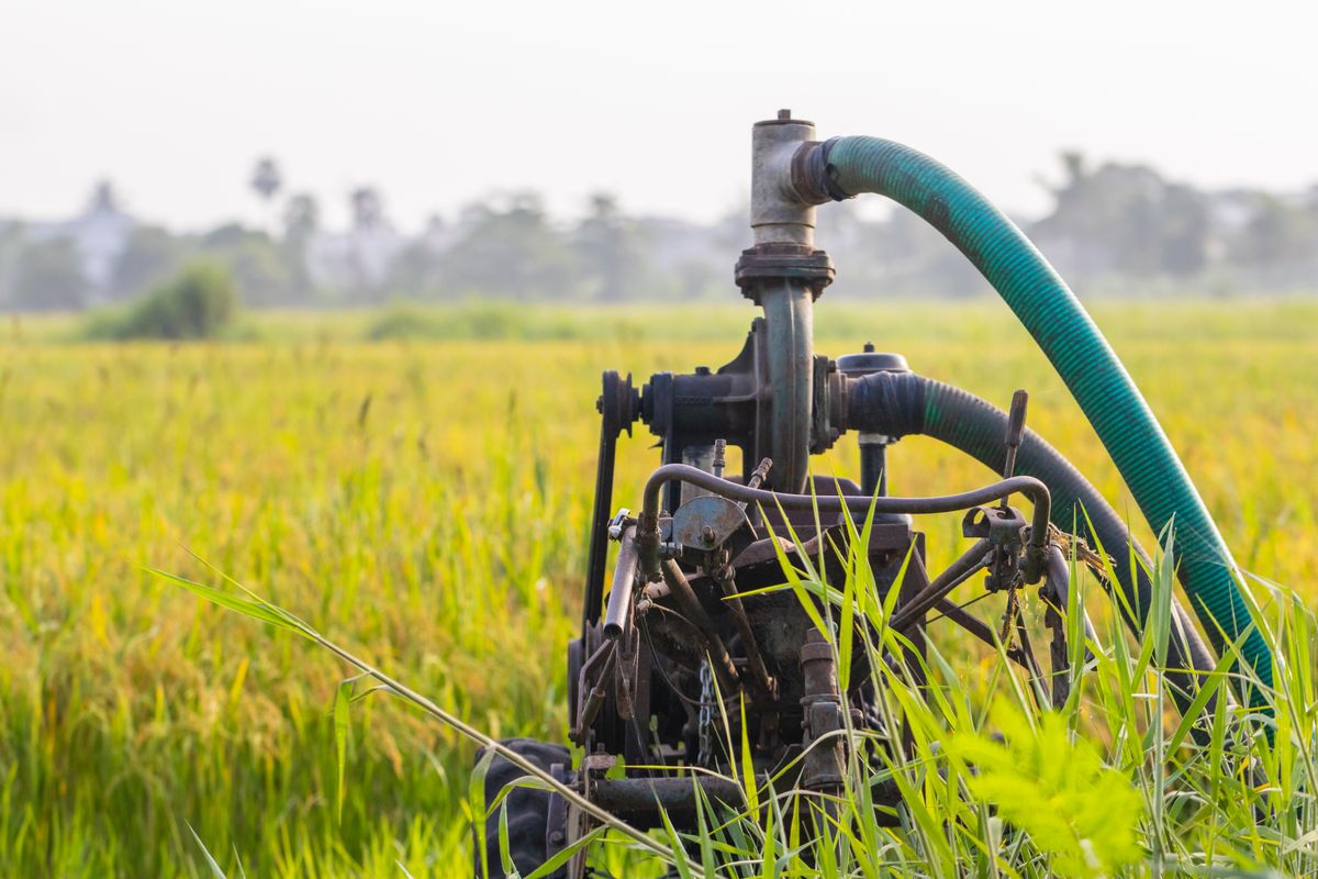 Diesel-powered water pump beside a green field, the private well supply where hydrogen sulfide odour usually originates