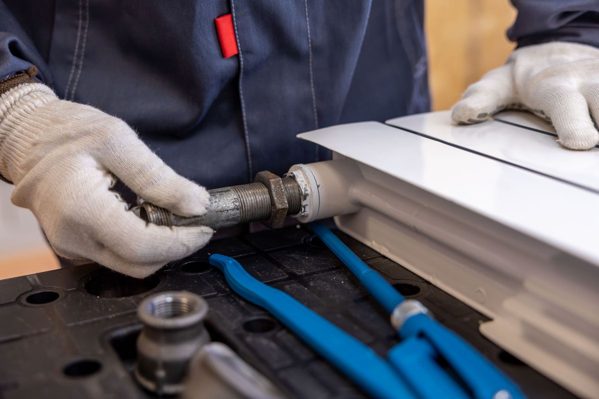 Technician fitting pipework with hand tools, the point at which a softener tank repair becomes a professional job