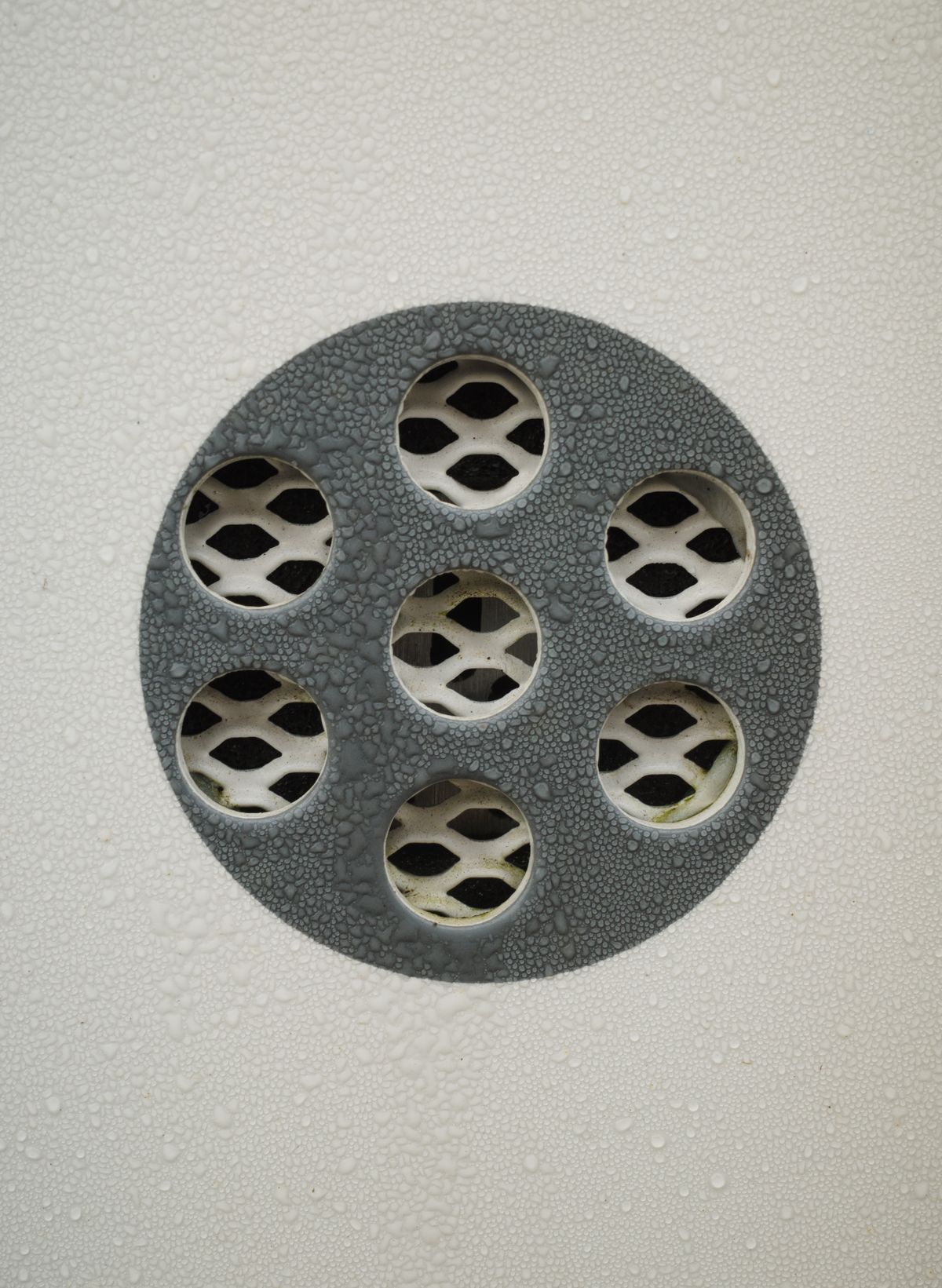 Water droplets scattered across a metal drain surface, the kind of residual wetness to check for at the discharge end after a softener drain line repair