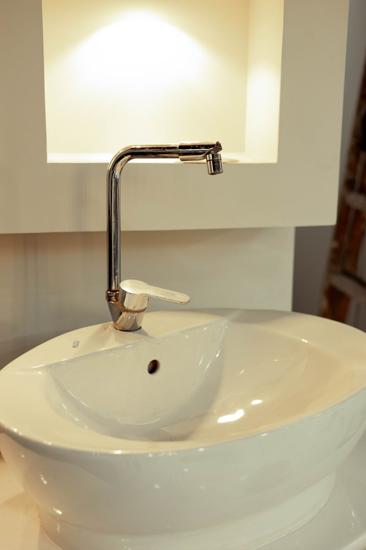Chrome mixer tap over a white ceramic basin, a cold-water fixture where salt-free conditioned water from a Watts OneFlow Plus can still leave hard water spots