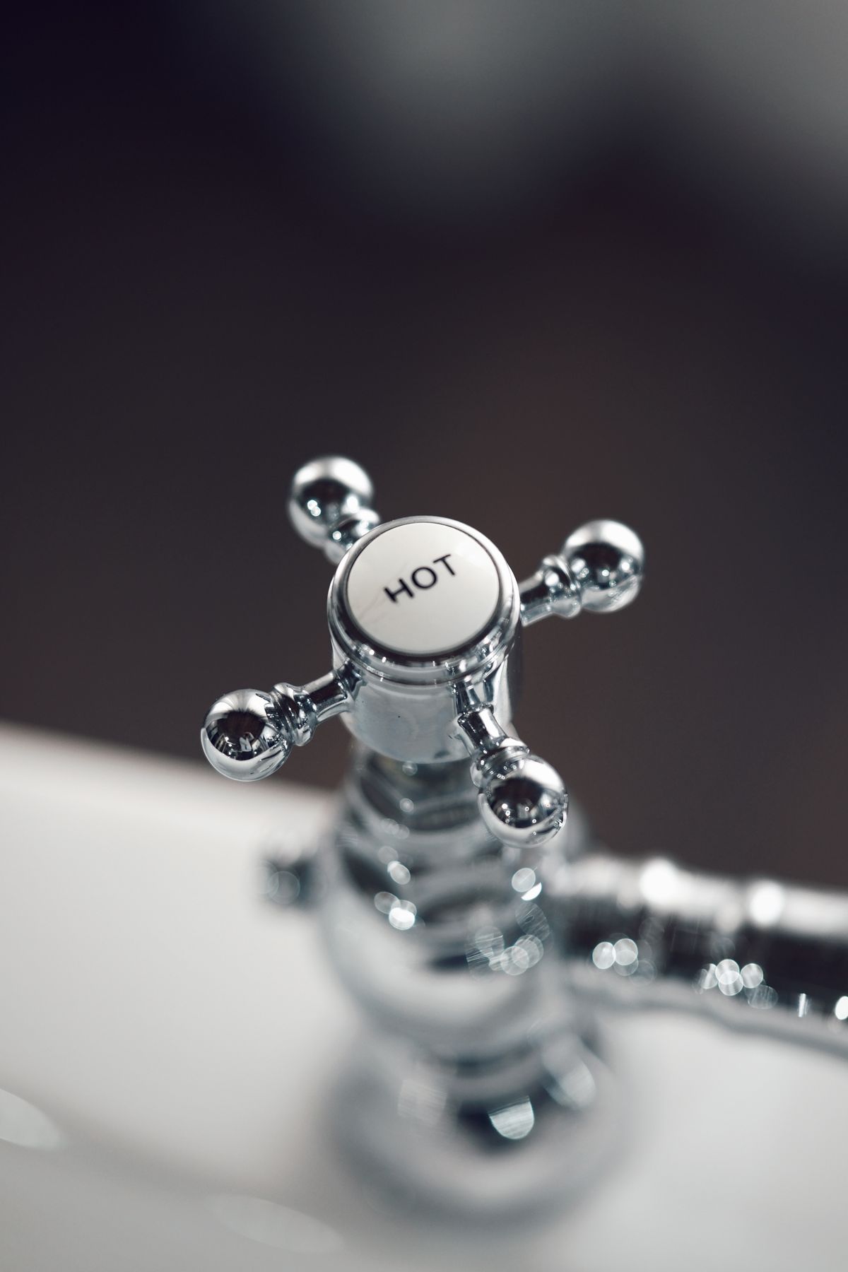 Close-up of a chrome faucet handle labelled Hot, the side of the tap where hot water causes more scale than cold