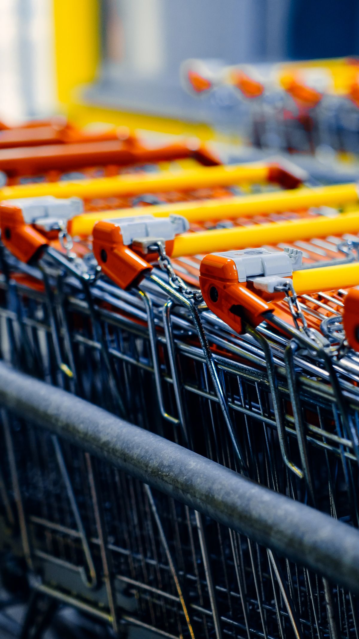 Stacked shopping carts with orange and yellow handles at a big-box store, where the same cabinet water softener can carry a different badge and price