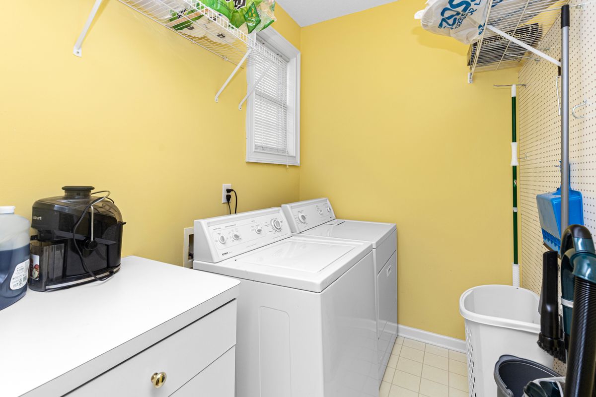 Small laundry room with a top-load washer and dryer, a wall outlet beside the window and wire shelving above