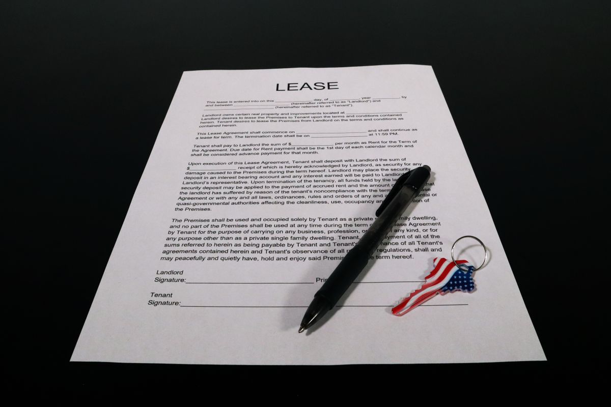 Printed residential lease with landlord and tenant signature lines, a pen and a keyring, the document that sets water softener duties in a rental