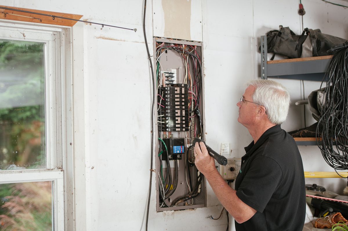 Electrician examining a residential fuse box indoors, the point at which a persistent softener error code becomes a job for a trained technician
