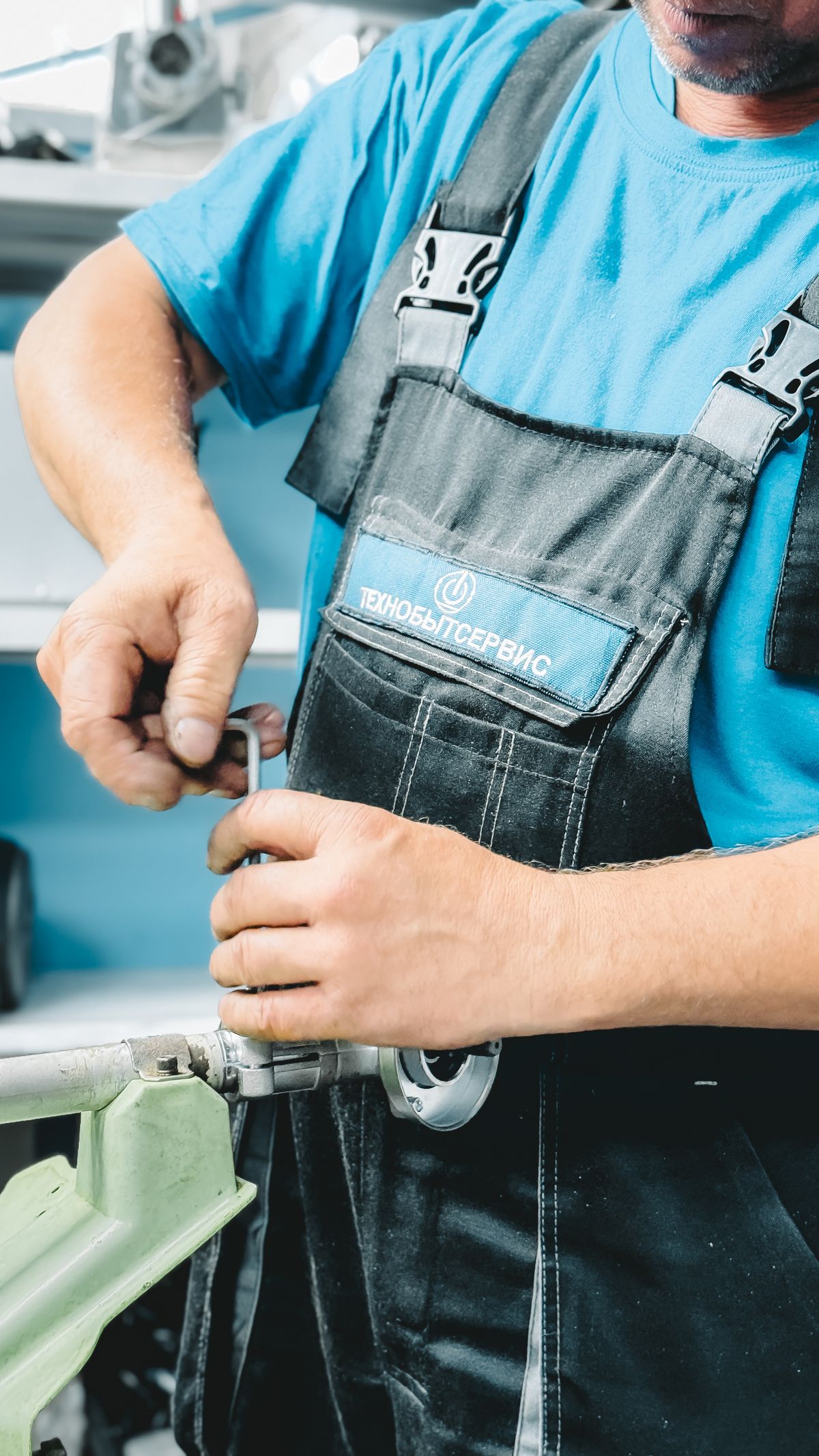 Plumber in blue overalls working on a pipe repair with a wrench, the kind of work needed when softener resin escapes into household plumbing