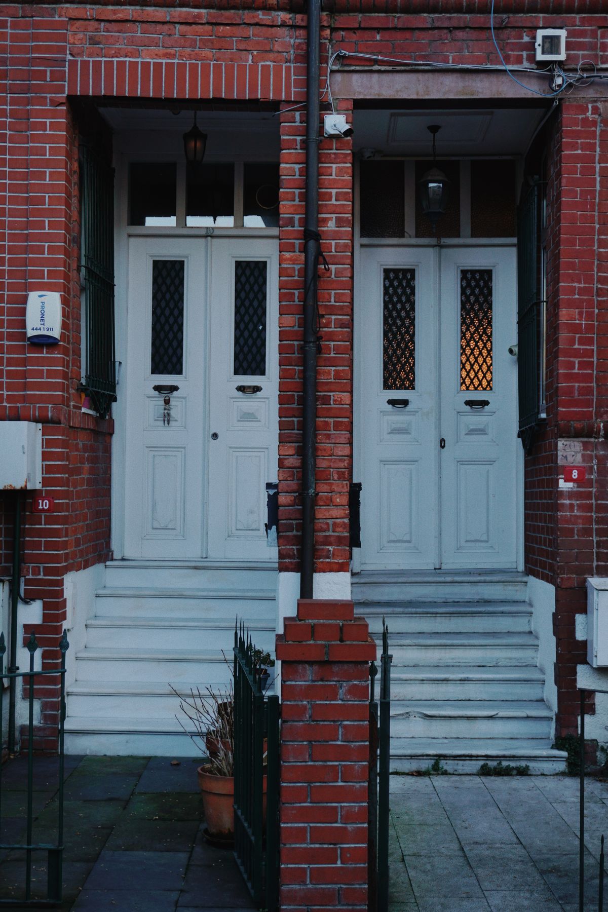 Red brick duplex with two side-by-side white front doors and separate steps, two dwelling units that can share one water softener