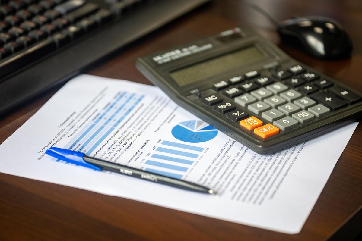 Calculator resting on a printed report with charts and a pen, representing the arithmetic of sizing a softener from a hardness report